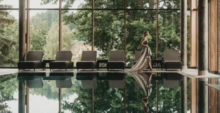 The best references for our hotel marketing Woman in a long dress beside an indoor pool with loungers and a view of greenery