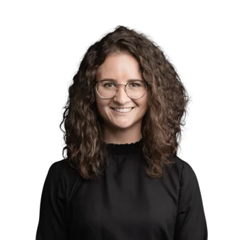 Stephanie Hasler | Lead Customer Success Management Porträt einer Frau mit lockigem Haar und Brille in schwarzem Oberteil