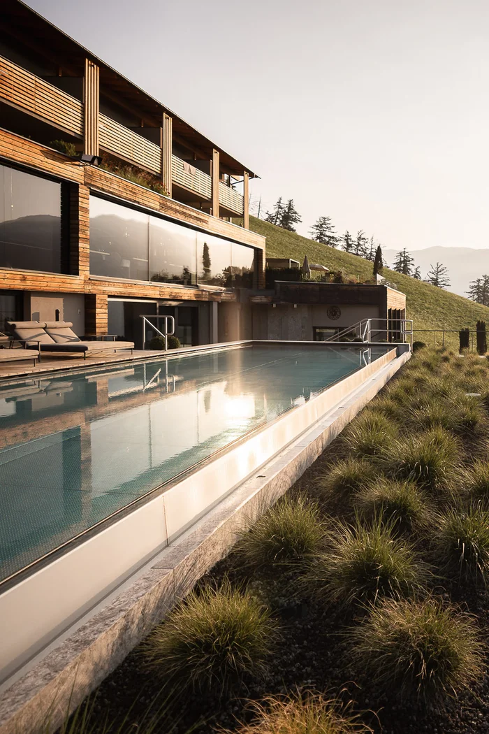 Brandnamic: Hotellösungen von Hospitality-Experten Modernes Haus mit langem Außenschwimmbad und Grünflächen am Hang