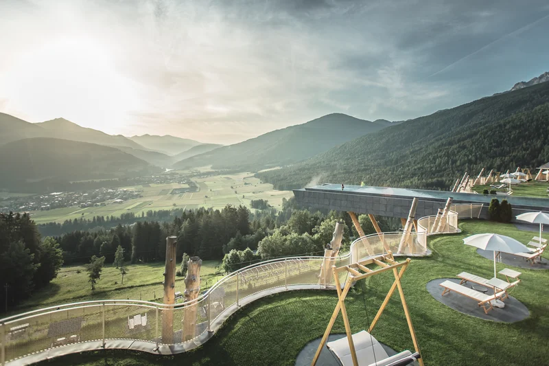 Eine Website mit Stil – made by Brandnamic Luxuriöse Terrasse mit Schaukeln, Liegestühlen und Infinity-Pool in den Bergen