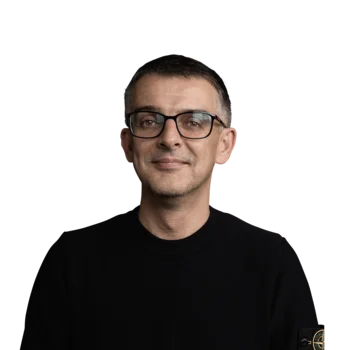 Ralf Kohler | Head of Visual Communication Design Porträt eines lächelnden Mannes mit schwarzem Pullover und Brille vor weißem Hintergrund