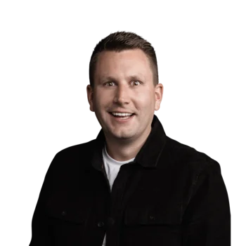 Lorenz Überegger | Sales Consultant Lächelnder Mann mit kurzem Haar und schwarzem Hemd vor weißem Hintergrund