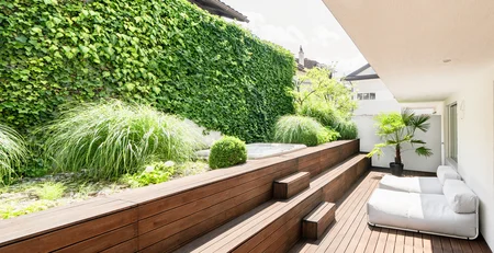 The best references for our hotel marketing Modern balcony with wooden deck, green plants, and white seating furniture