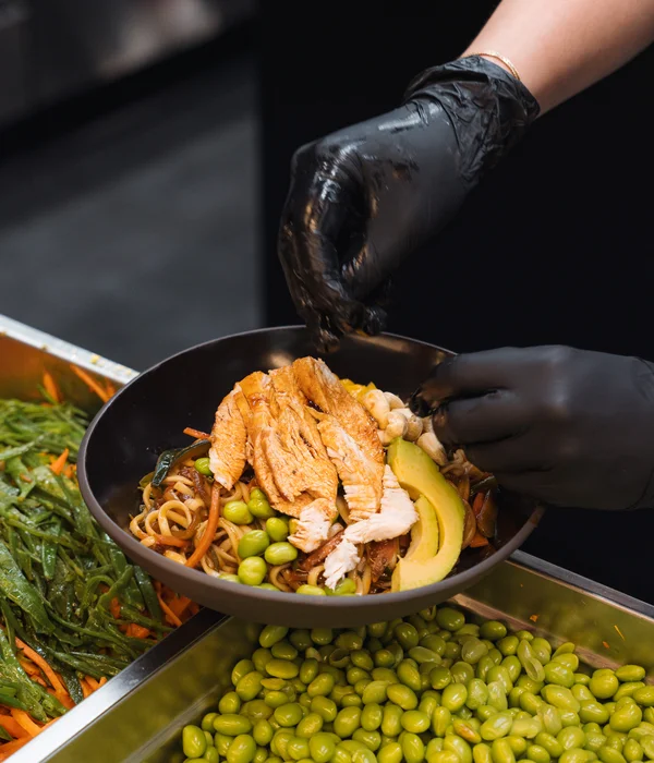 Seminarraum in Südtirol zum Mieten gesucht? Der Brandnamic Campus ist ideal Person mit schwarzen Handschuhen richtet gesunden Teller mit gebratenem Hähnchen und Gemüse an