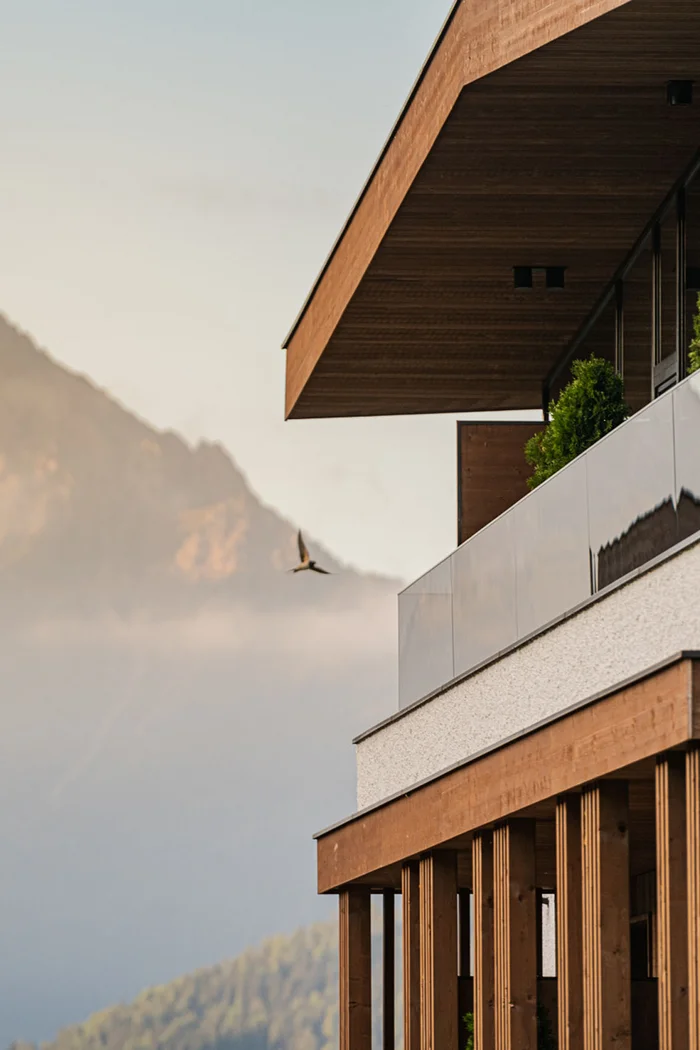 Brandnamic: Hotellösungen von Hospitality-Experten Moderne Holzbauten mit Berg im Nebel und Vogel im Flug