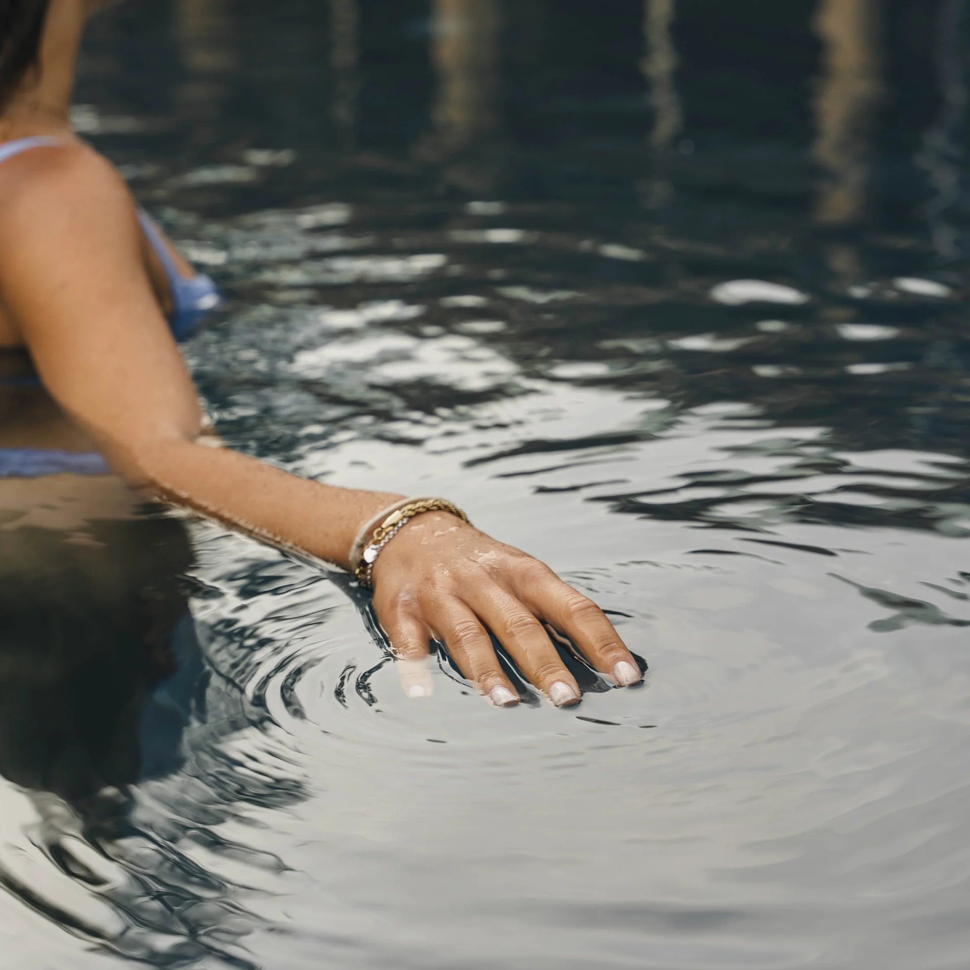 Erfolgreiches Marketing aus Brixen Frau berührt Wasseroberfläche in einem Pool mit sanften Wellen