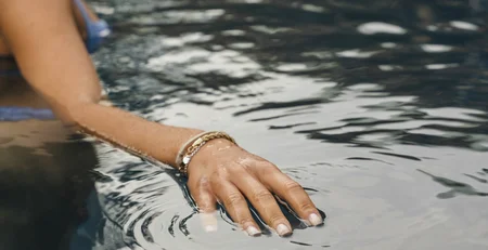 The best references for our hotel marketing Woman touching water surface in a pool with gentle ripples