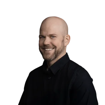 Nils Reddig | Business Operations Manager Lächelnder Mann mit Glatze und Bart in schwarzem Hemd vor weißem Hintergrund