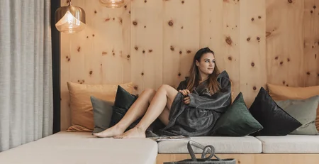 Die besten Referenzen für unser Hotelmarketing Frau entspannt auf einer Holzbank mit Kissen in modernem Raum