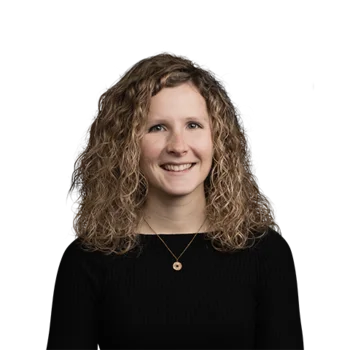 Julia Althuber | SEO Manager Porträt einer lächelnden Frau mit lockigem Haar und schwarzem Oberteil