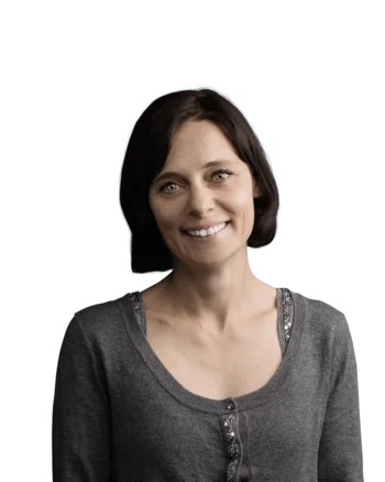 Barbara Zöll | Head of Copywriting Fröhliche Frau mit kurzen braunen Haaren und grauem Pullover