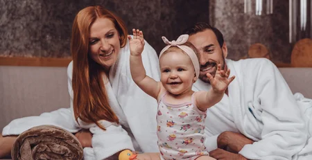 Die besten Referenzen für unser Hotelmarketing Glückliche Familie mit Baby und Quietscheente auf Sofa zu Hause