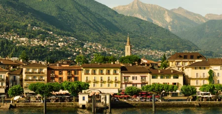 The best references for our hotel marketing View of colorful lakeside houses with mountains in the background