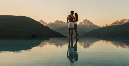The best references for our hotel marketing Couple in infinity pool overlooking mountains at sunset