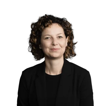 Carmen Marcher | Business Process Manager Porträt einer lächelnden Frau mit lockigem Haar in schwarzem Blazer