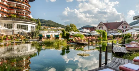 The best references for our hotel marketing Hotel with pond, lounge chairs, and umbrellas on a sunny day