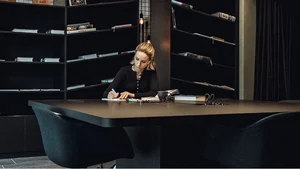 Brandnamic: Hotellösungen von Hospitality-Experten Frau schreibt Notizen an einem großen Tisch in einem modernen Raum mit Bücherregalen