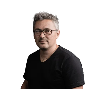 Julian Stricker | Senior Software Developer Porträt eines Mannes mit Brille und grau meliertem Haar in schwarzem T-Shirt