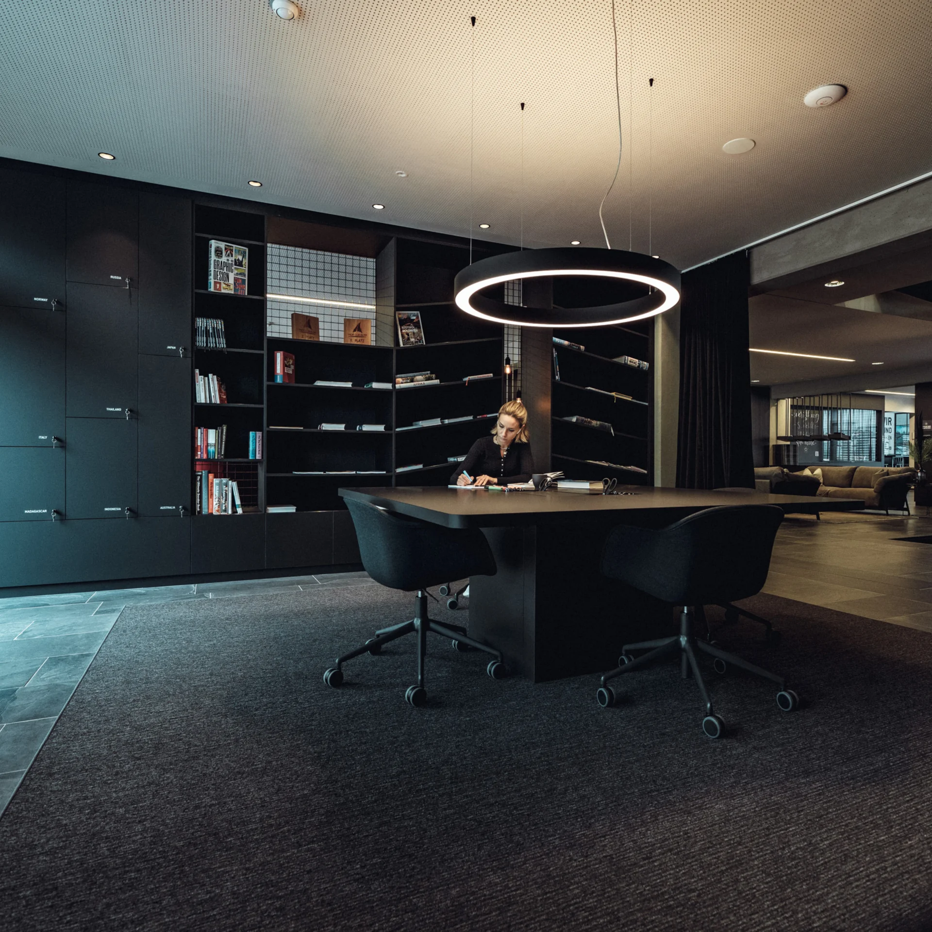 Alles Interessante rund um Online-Marketing für Hotels Frau sitzt an einem Tisch in modernem Büro mit Bücherregalen und Beleuchtung