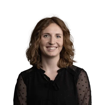 Marina Niccolini | Senior Copywriter & Translator Fröhliche Frau mit lockigem braunem Haar und schwarzer transparenter Bluse