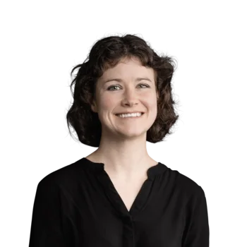 Lisa Hoggard | Senior Copywriter & Translator Frau mit kurzen lockigen Haaren in schwarzem Hemd lächelnd vor weißem Hintergrund