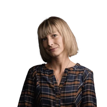 Irene Reiterer | Senior Visual Communication Designer Porträt einer lächelnden Frau mit karierter Bluse vor weißem Hintergrund