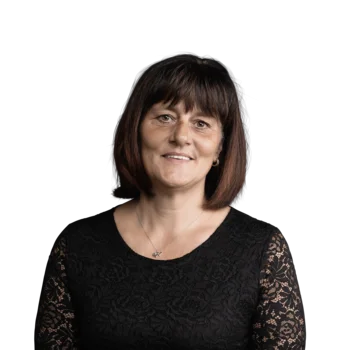 Reinhilde Gostner | Campus Support Porträt einer lächelnden Frau mit schwarzer Spitzenbluse vor weißem Hintergrund