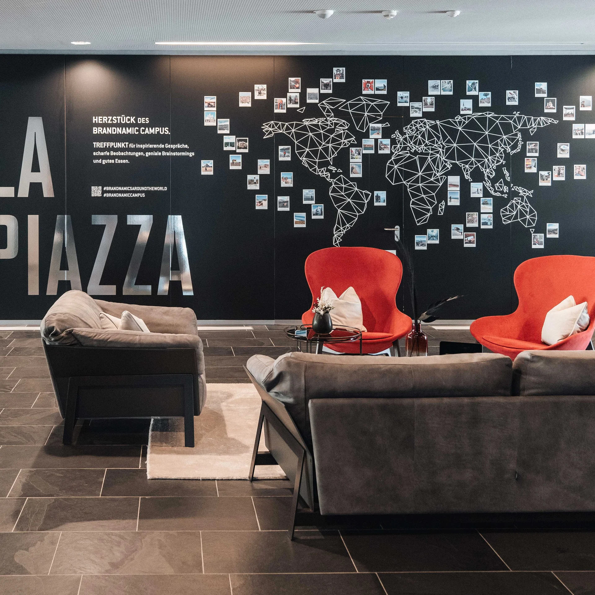 Seminarraum in Südtirol zum Mieten gesucht? Der Brandnamic Campus ist ideal Moderne Lobby mit Sitzbereich und Weltkarte auf der Wand