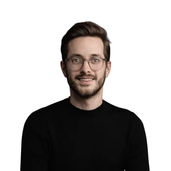 Damiano Ferratello | Customer Success Manager Porträt eines lächelnden jungen Mannes mit Brille und schwarzem Pullover vor weißem Hintergrund