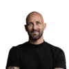 Alles Interessante rund um Online-Marketing für Hotels Porträt eines lächelnden, tätowierten Mannes mit schwarzem T-Shirt vor weißem Hintergrund
