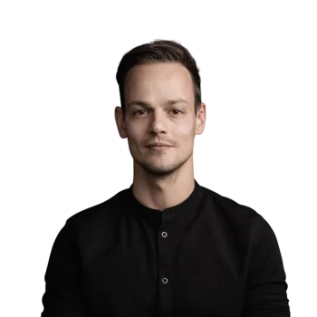 Hannes Kinigadner | Division Manager Advertising Porträt eines jungen Mannes mit schwarzem Hemd vor weißem Hintergrund