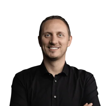 Matthias Prader | CFO Lächelnder Mann in schwarzem Hemd vor weißem Hintergrund