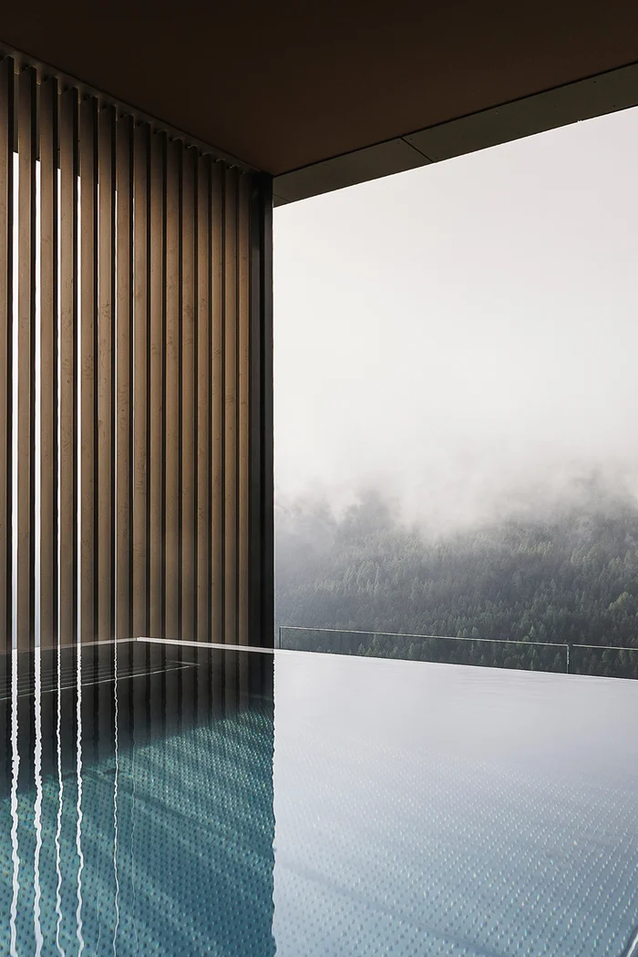 Brandnamic: Hotellösungen von Hospitality-Experten Infinity-Pool mit Holzwand und Nebel über bewaldeten Bergen