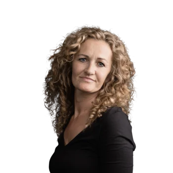 Christine Putzer | Campus Support Frau mit lockigem blonden Haar und schwarzem Oberteil vor weißem Hintergrund