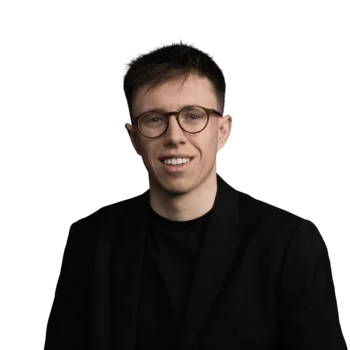 Fabian Haas | Sales Consultant Junger Mann mit brauner Brille in schwarzem Anzug vor weißem Hintergrund