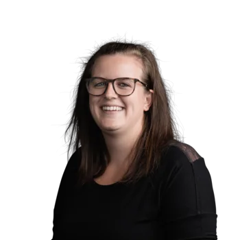 Sara Tratter | Campus Support Lächelnde Frau mit Brille und langen dunklen Haaren vor weißem Hintergrund