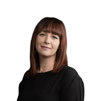 Stephanie Ganterer | Hotelcoach Academy Porträt einer Frau mit rotem Haar in schwarzem Oberteil vor weißem Hintergrund