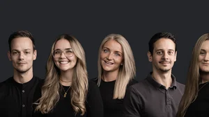 Brandnamic: Soluzioni hotel dagli esperti per il settore alberghiero Ritratto di un gruppo di cinque giovani adulti sorridenti con sfondo scuro