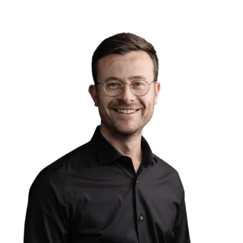 Harald Kager | Senior Consultant Lächelnder Mann mit Brille in schwarzem Hemd vor weißem Hintergrund