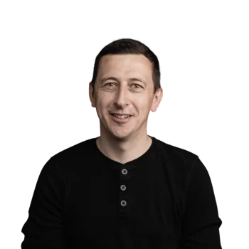 Tobias Lerchegger | Campus Support Porträt eines lächelnden Mannes mit schwarzem Langarmshirt vor weißem Hintergrund