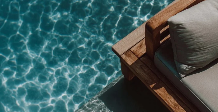 Hotelberatung: Experten für die Hospitalitybranche Holzliege mit Kissen am Rand eines Pools mit klarem blauem Wasser