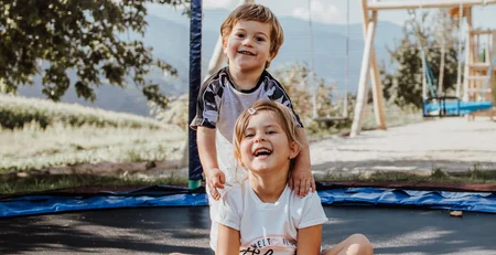 The best references for our hotel marketing Two happy children playing on an outdoor trampoline on a sunny day